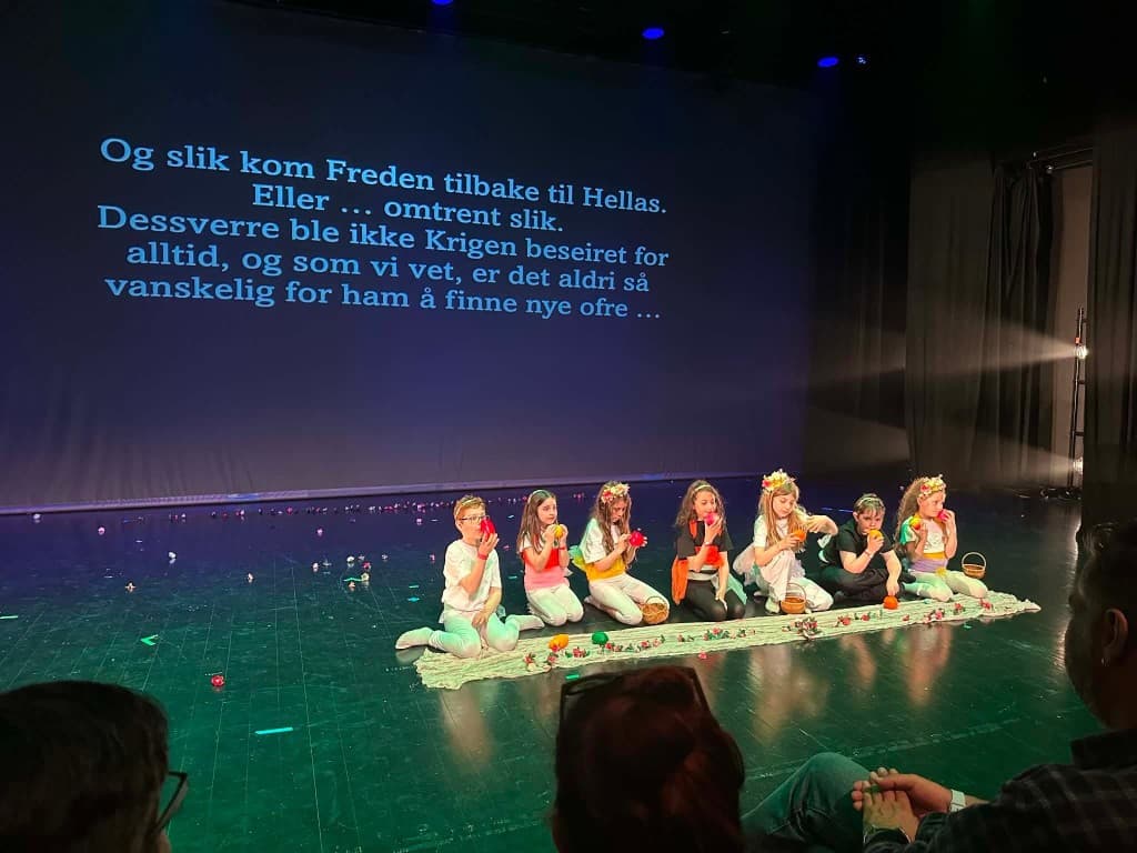 Barn sittende på scenen under forestillingen Fred